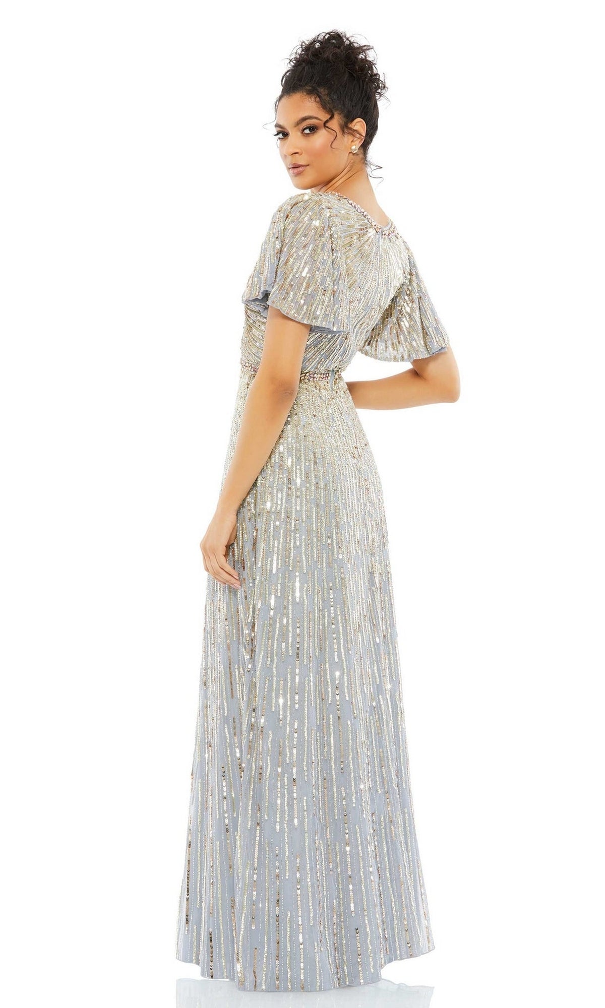 A woman stands slightly turned to the side against a white background, wearing the Mac Duggal Long Formal Dress 5538—an elegant floor-length gown with silver and gold sequins and flutter sleeves.